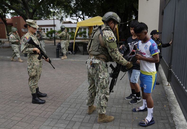 Soldiers search student backpacks on school grounds in downtown Guayaquil, Ecuador, Friday, Aug. 18, 2023. Ecuadorians will elect a new president on Sunday, less than two weeks after the South American country was rocked by the assassination of one of the candidates.  (AP Photo/Martín Mejía)