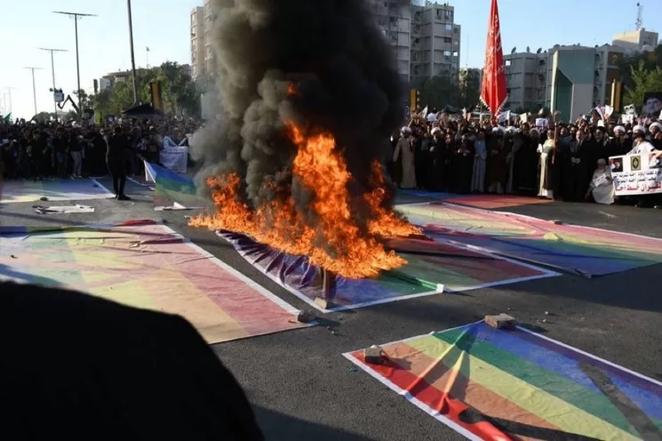 Manifestantes iraquíes incendian una bandera de la comunidad LGBT durante una protesta en Bagdad. Foto tomada de Twitter.