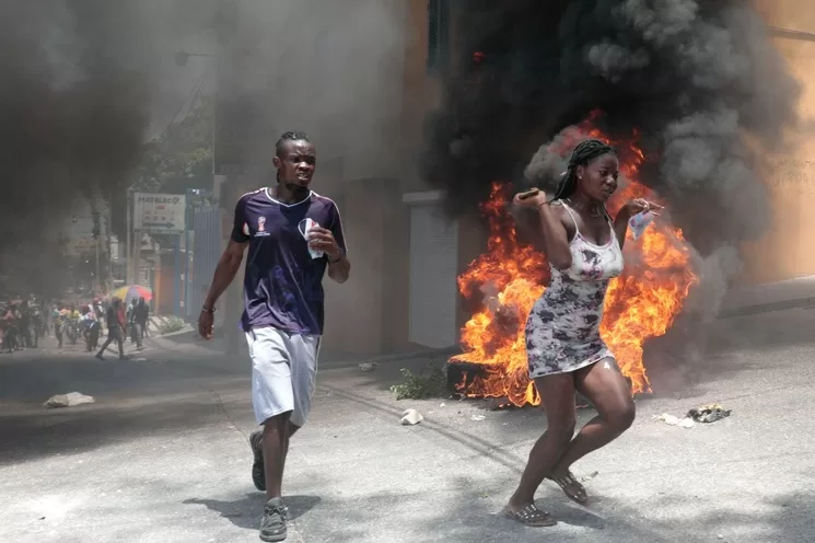 Manifestantes escapan del gas lacrimógeno que lanzó la policía ayer, cuando se dirigían a la residencia oficial del primer ministro haitiano, Ariel Henry, para exigir un freno a la violencia de las pandillas. Foto Ap