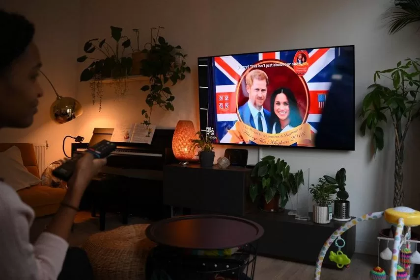 A woman poses while watching an episode of the recently released Netflix documentary series Harry and Meghan about Britain's Prince Harry, Duke of Sussex, and Britain's Meghan, Duchess of Sussex, in London on December 8, 2022. 
