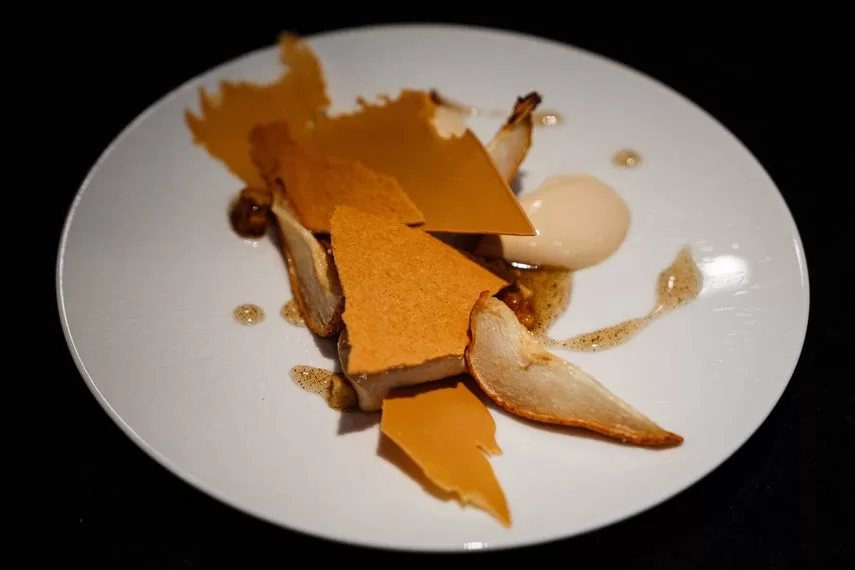 A photograph taken in Paris on March 1, 2024 shows a pure fondant dessert with blond chocolate, oven-roasted apples and a Tahitian vanilla cream prepared by French pastry chef and creative director of the Valrhona chocolatier, Frederic Bau.  