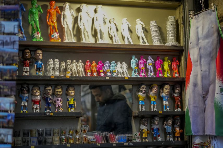 A vendor sells souvenirs of Michelangelo's 16th-century David statue at a kiosk in central Florence, Italy, Monday, March 18, 2024. 