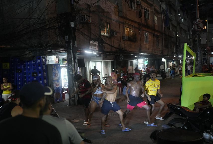 Young people illuminated by the headlight of a motorcycle perform the passinho style of street dance in the Rocinha favela of Rio de Janeiro, Brazil on April 11, 2024.