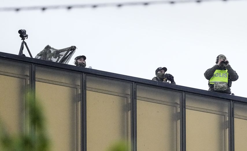 Police officers watch from a rooftop as people line up for the second dress rehearsal of the first semi-final of the Eurovision Song Contest in Malmo, Sweden, Monday, May 6, 2024.