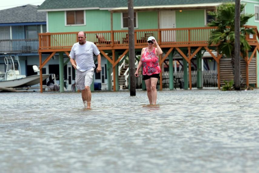 Adam Sides walks through a flooded street with his mother, Cindy, in the wake of Tropical Storm Alberto, Thursday, June 20, 2024, in Surfside Beach, Texas.