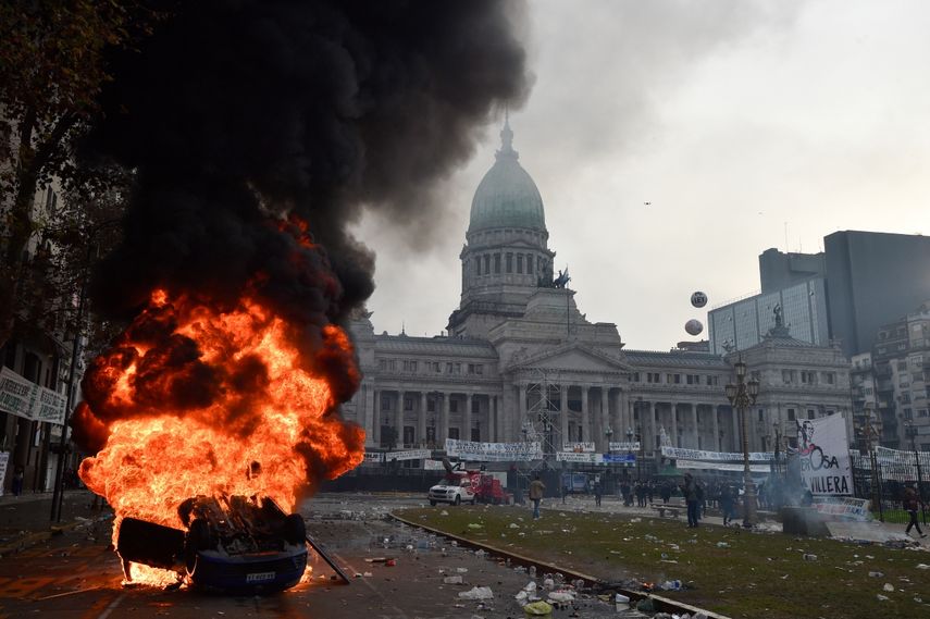 A car burns during clashes between police and anti-government protesters in front of Congress, where senators debate bills promoted by Argentine President Javier Milei in Buenos Aires, Argentina, Wednesday, June 12, 2024