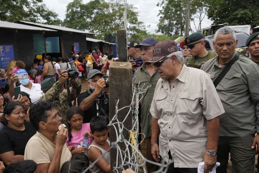 Panamanian President Jose Raul Mulino speaks with a Venezuelan migrant, left, and other migrants at a camp after they walked across the Darien Gap from Colombia, in Lajas Blancas, Panama, Friday, June 28, 2024.