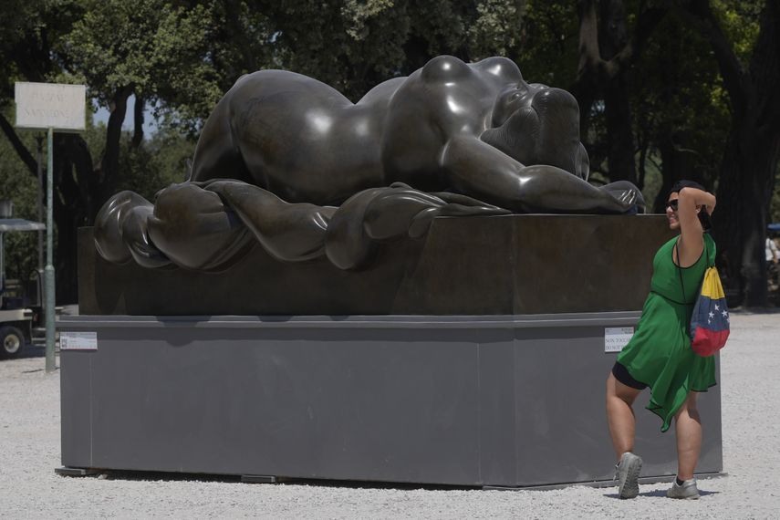 A woman poses for a photograph near the sculpture 